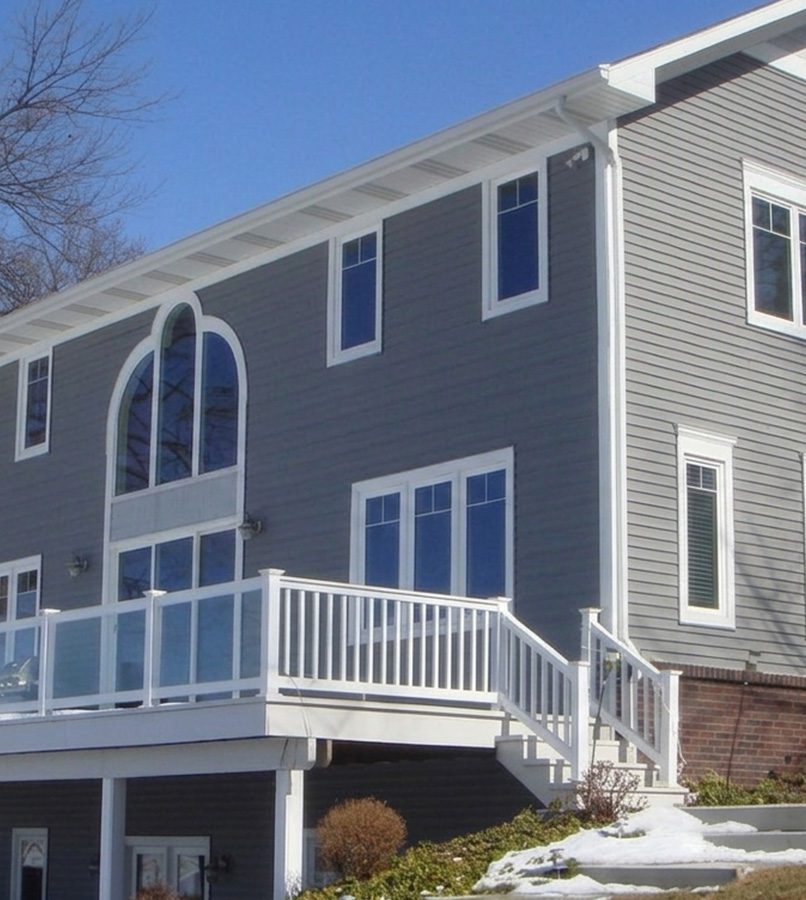 Gray house with large windows and balcony.