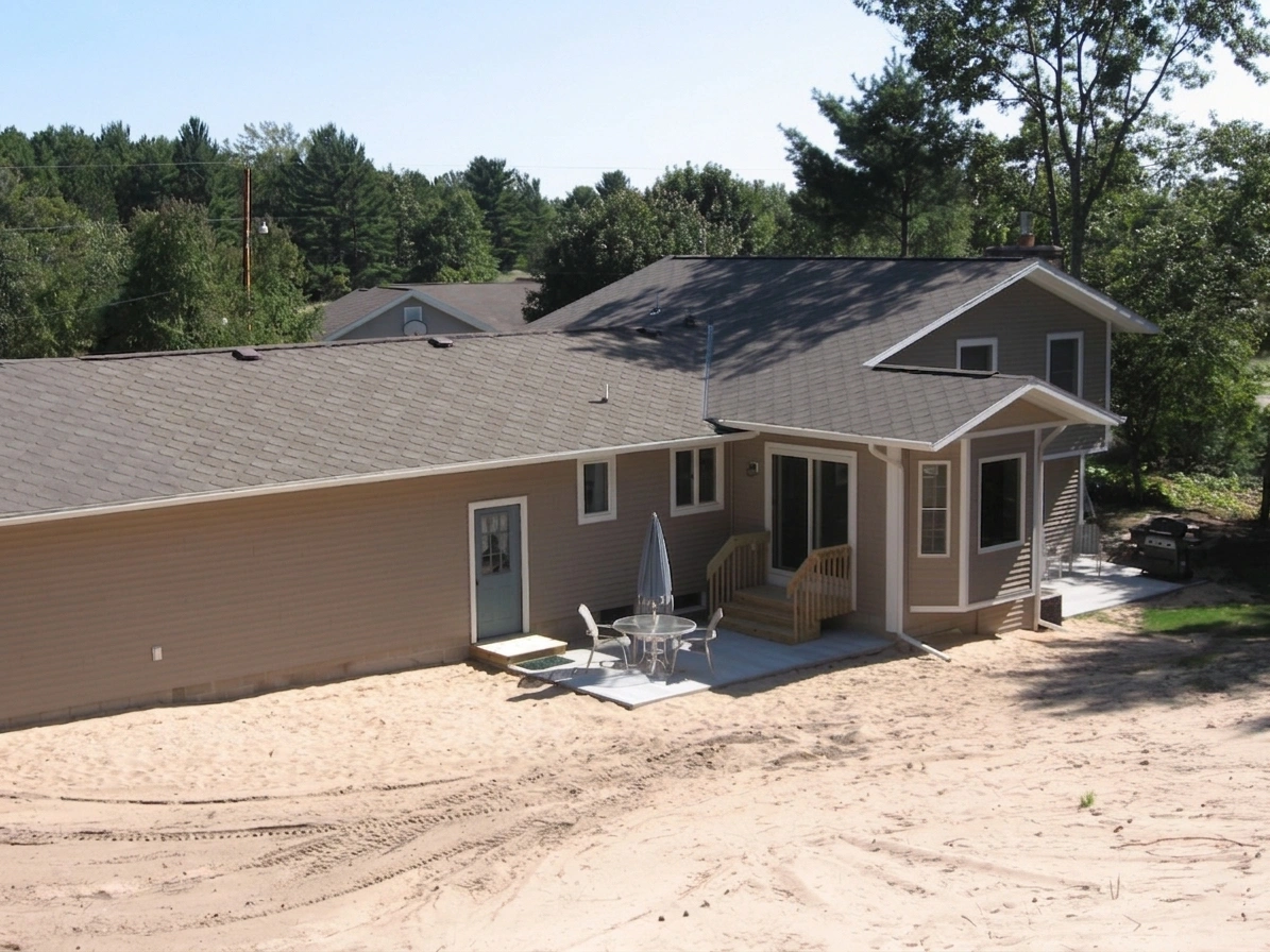 Single-story house with patio in sandy yard.