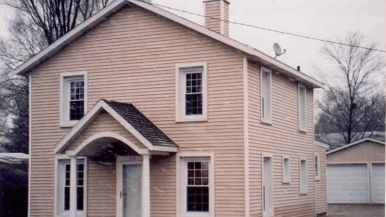 Two-story beige house with white trim.