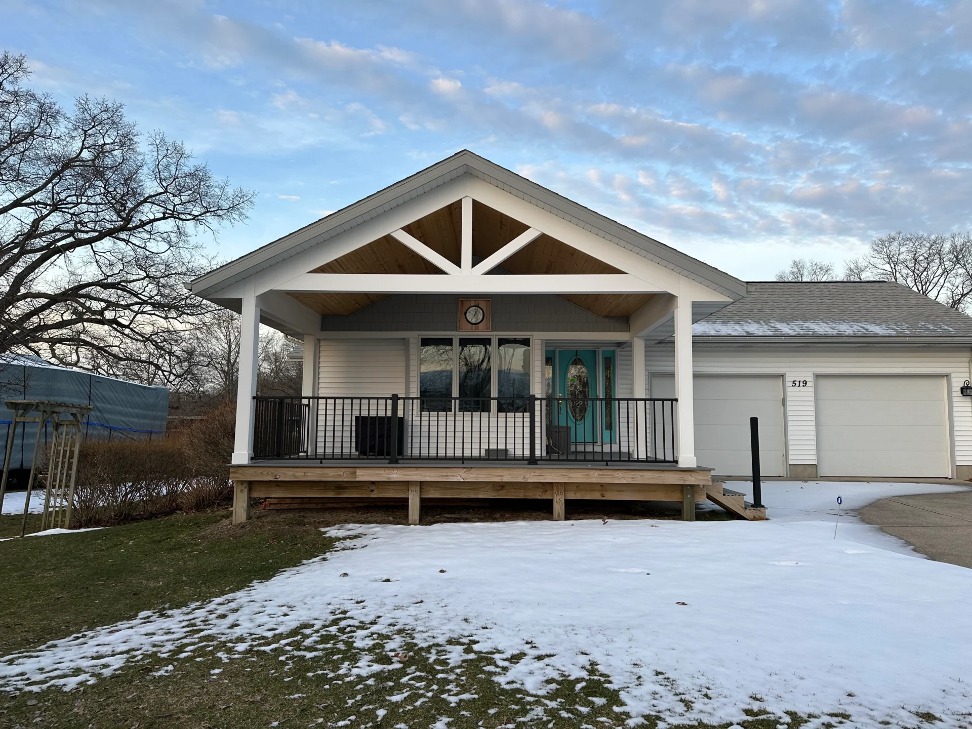 White house with porch in winter setting.