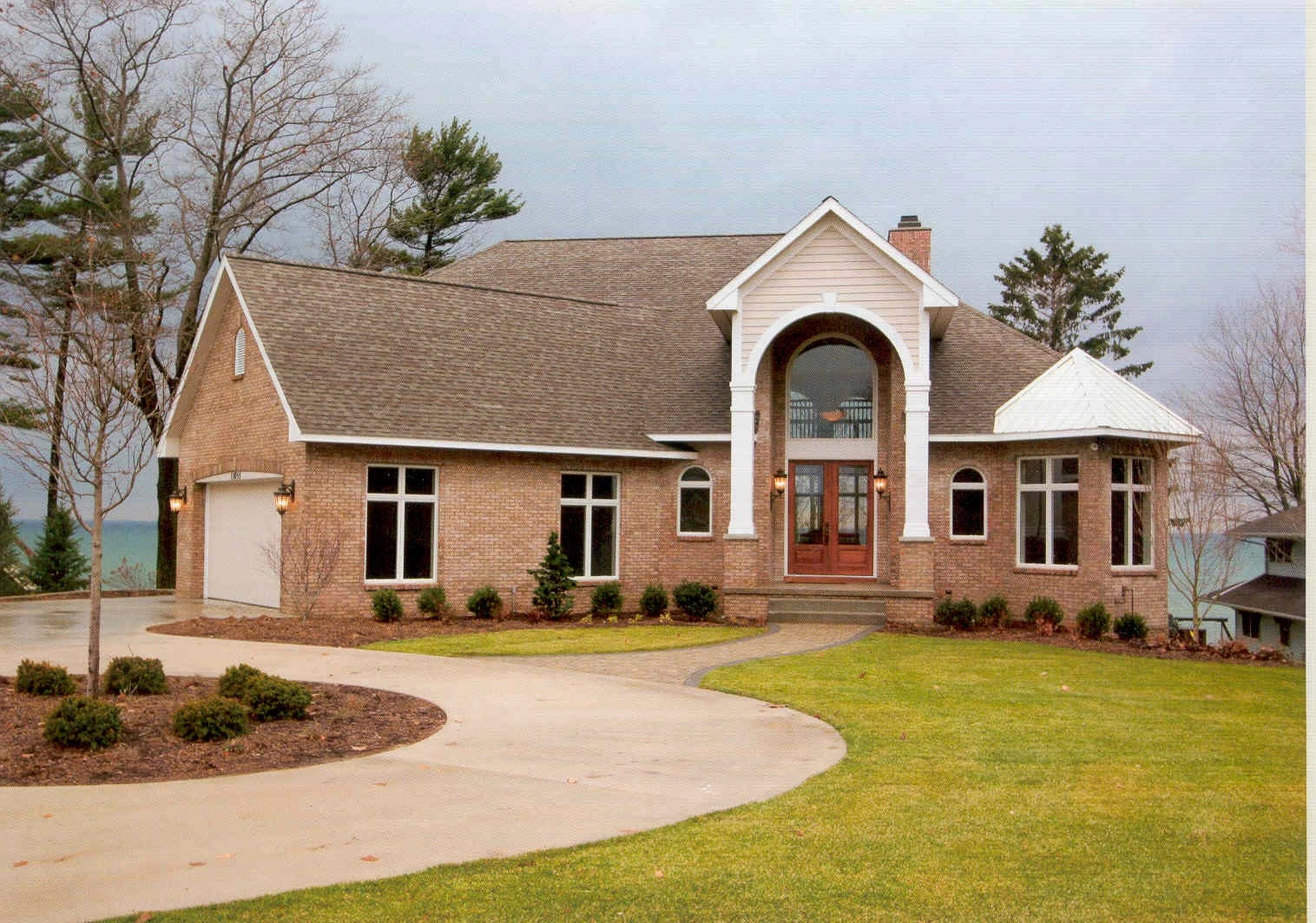 Brick house with arched entry and lawn.
