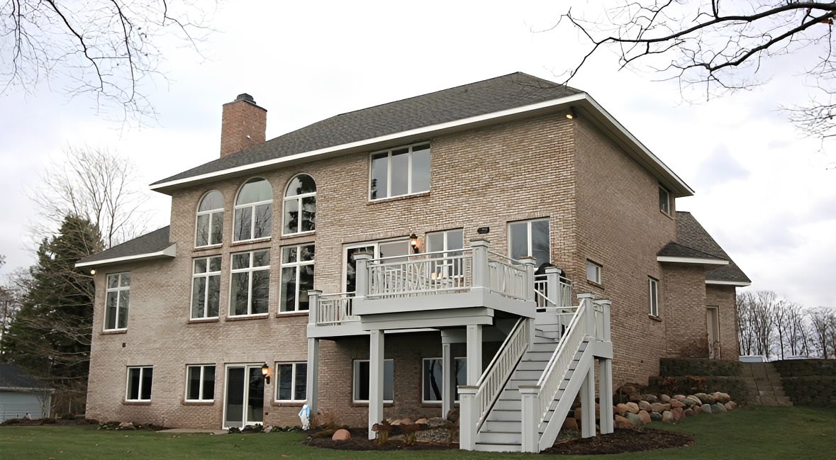 Brick house with large windows and balcony.