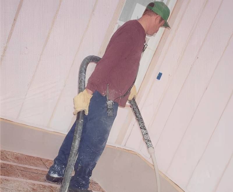 Worker using hose for wall insulation.