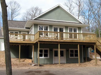 Elevated house with wooden deck and trees.