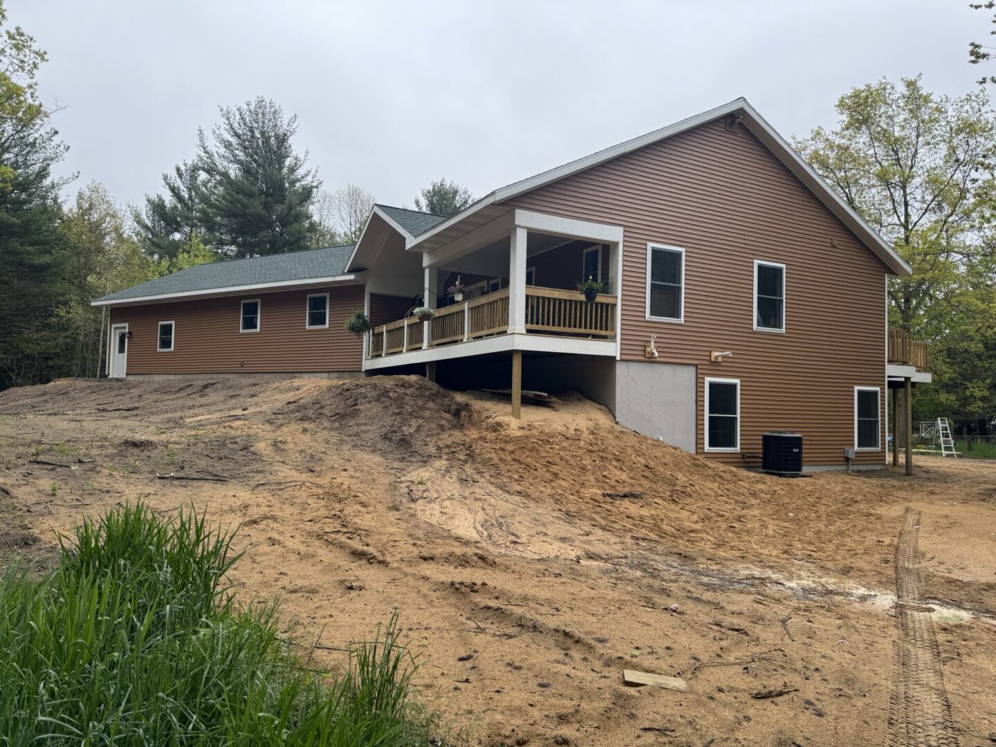Brown house with porch on sandy terrain.