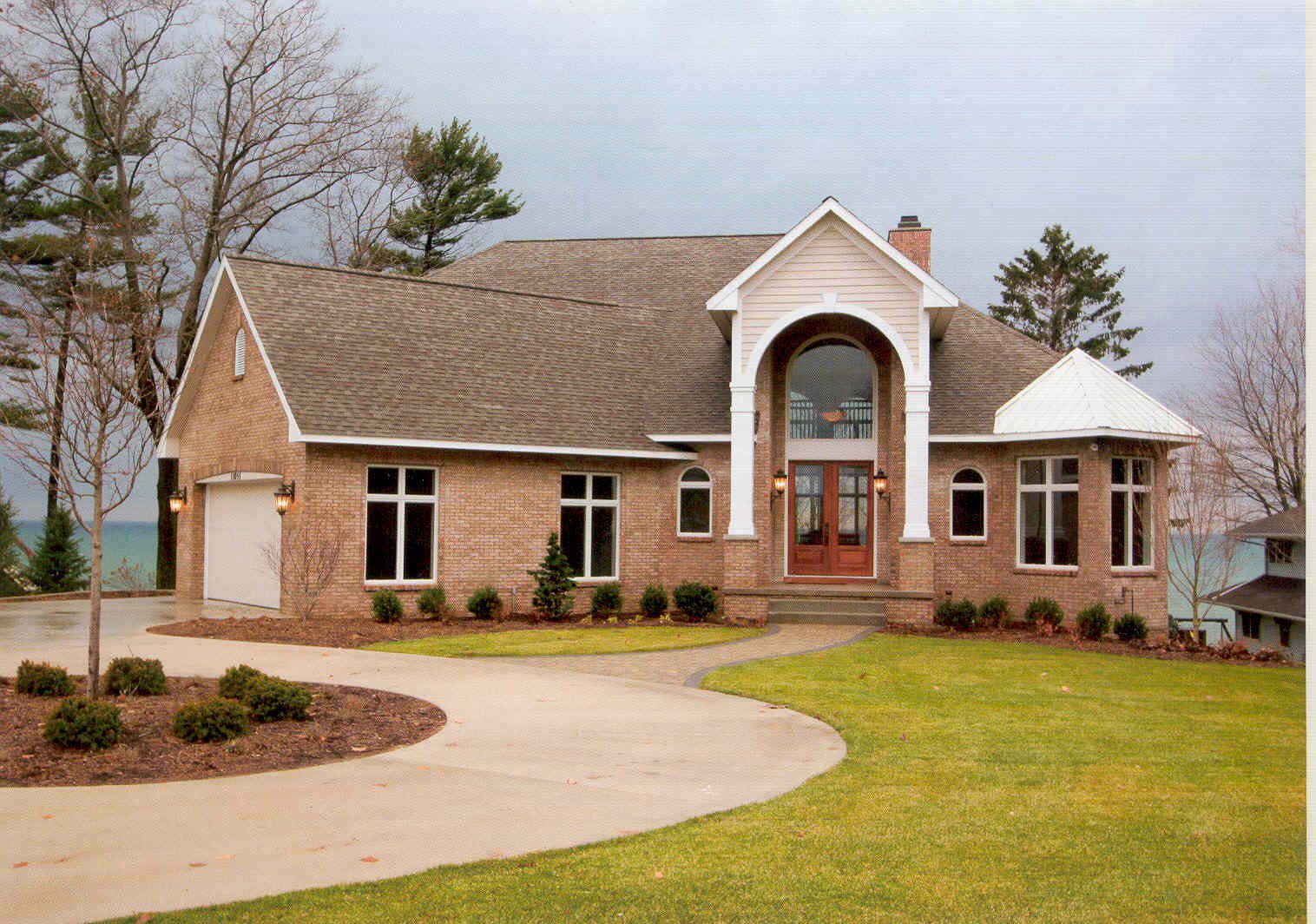 Brick house with archway and curved driveway.