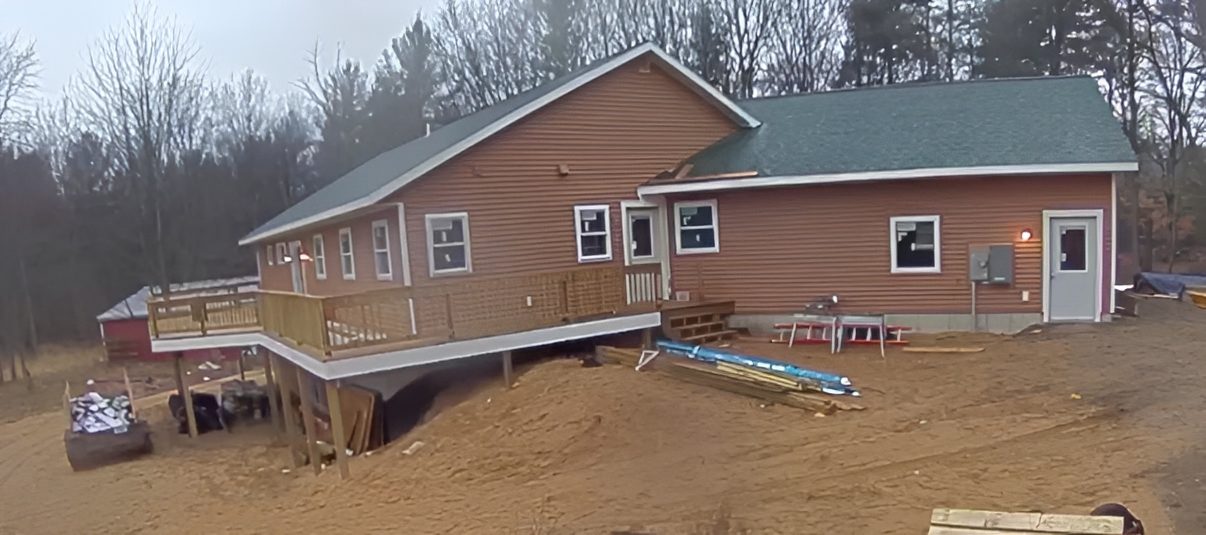 Brown house with deck in wooded area.